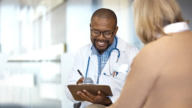 A physician taking notes with a patient